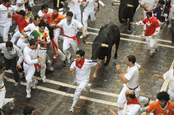 People dressed in white running from a bull