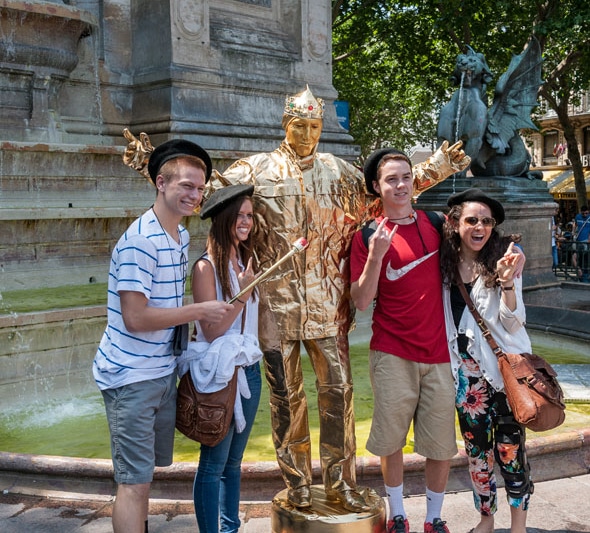 Young students taking a picture with a mime on a golden costume