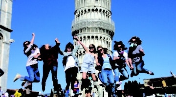 students jumping in front of the tower of pisa