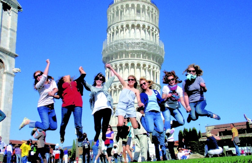 students jumping in front of the tower of pisa