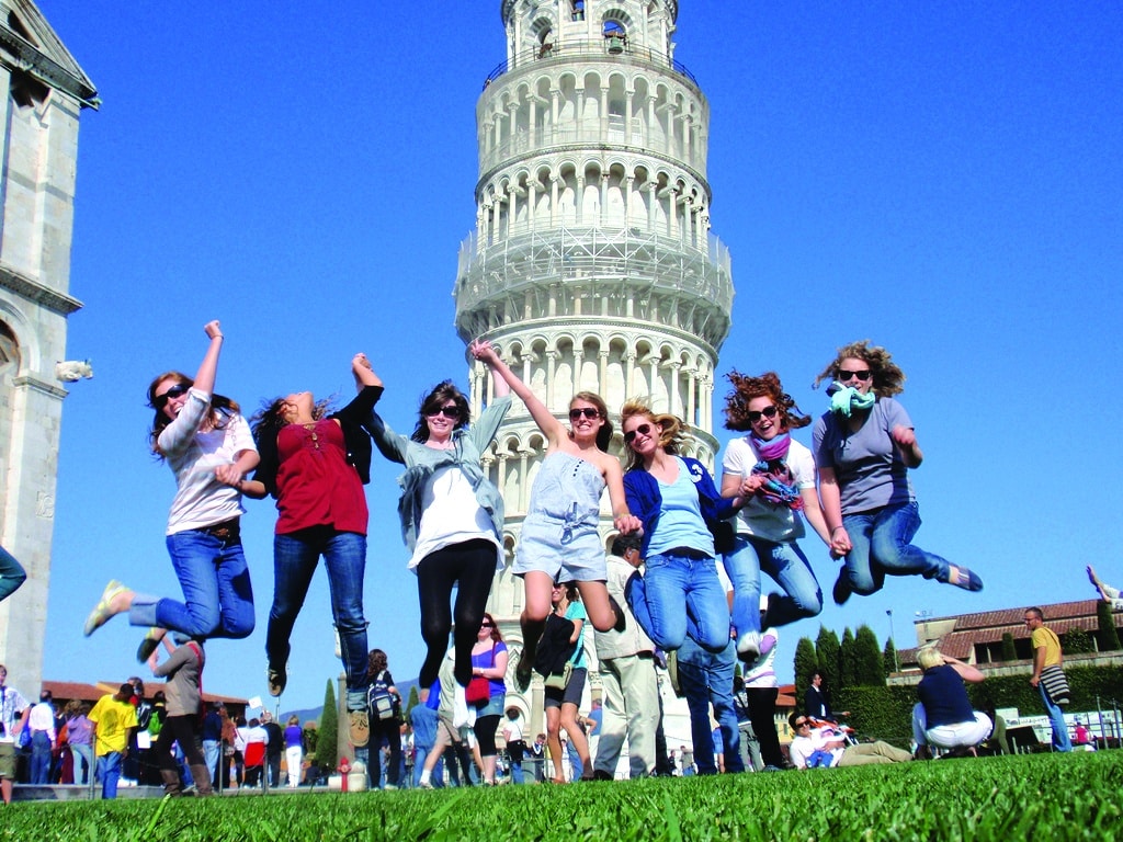 students jumping in front of the tower of pisa