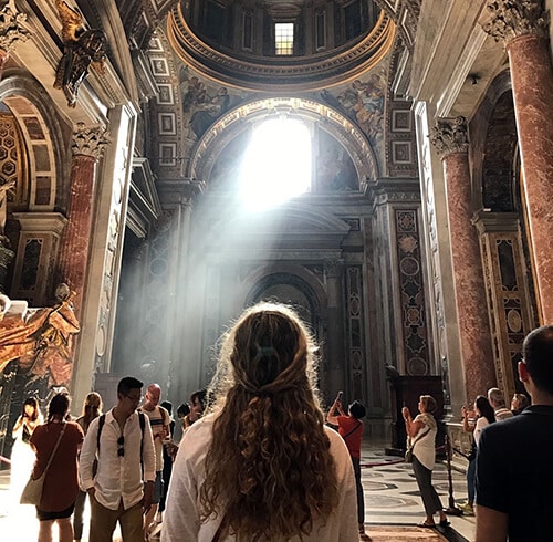 Student in italy basilica with light shining from window