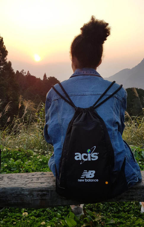 ACIS participant sitting on wood bench overlooking a sunrise