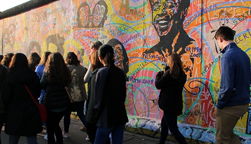 Students walk along the Berlin Wall