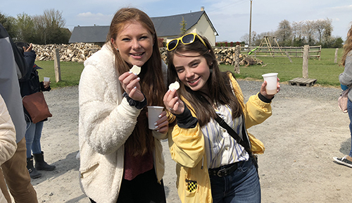 Two girls holding goat cheese from a farm in Normandy