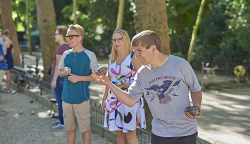 Students playing pétanque in a park in Paris