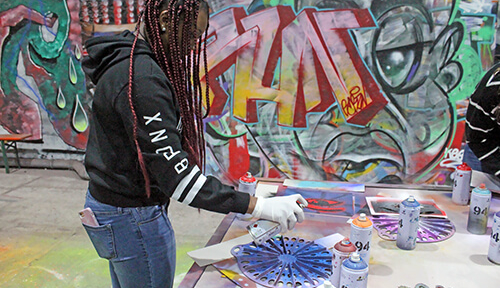 Student spray painting stencil at Berlin Street Art workshop