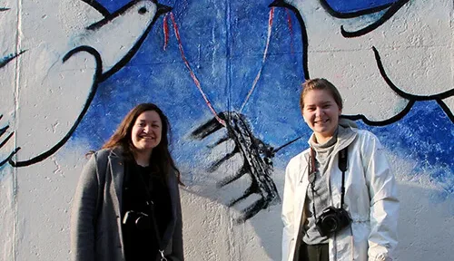 Students pose in front of a mural on the Berlin Wall