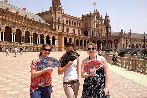 Students at the Seville Plaza holding fans