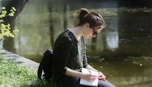 A girl sitting outside writing in a journal