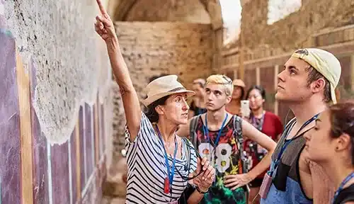Tour guide pointing to ancient wall in Pompeii, Italy