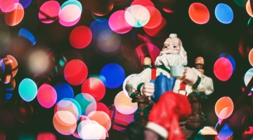 Santa figurine in front of blurry Christmas lights