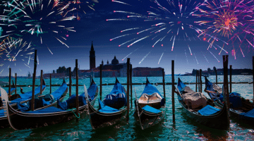 gondolas tied up under an evening sky of fireworks in venice