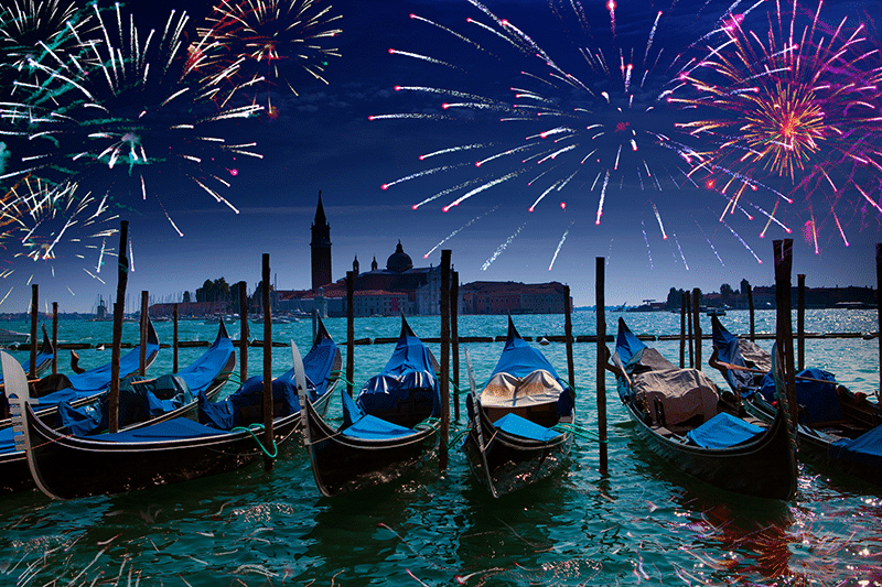 gondolas tied up under an evening sky of fireworks in venice