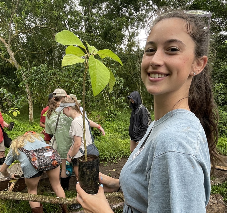 A student in Ecuador holding a sapling