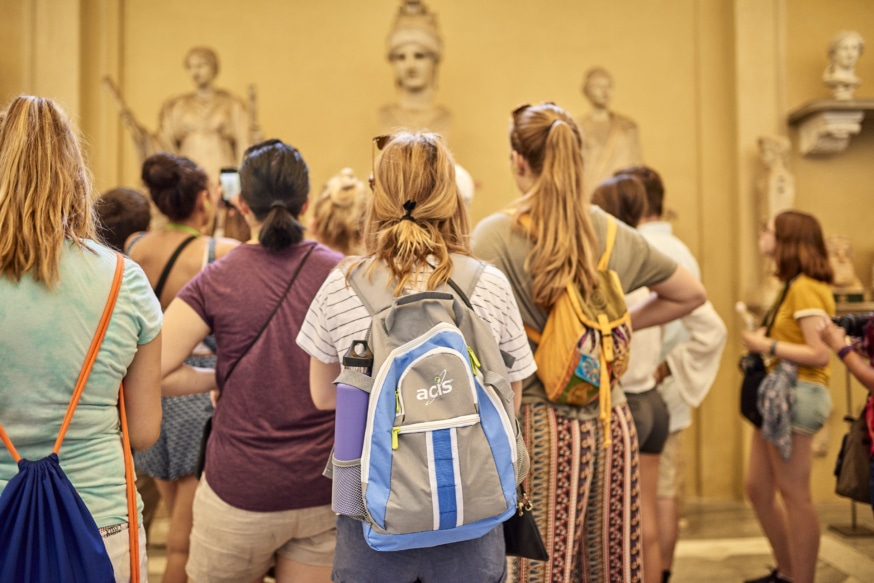 A student stands at a museum with an ACIS backpack
