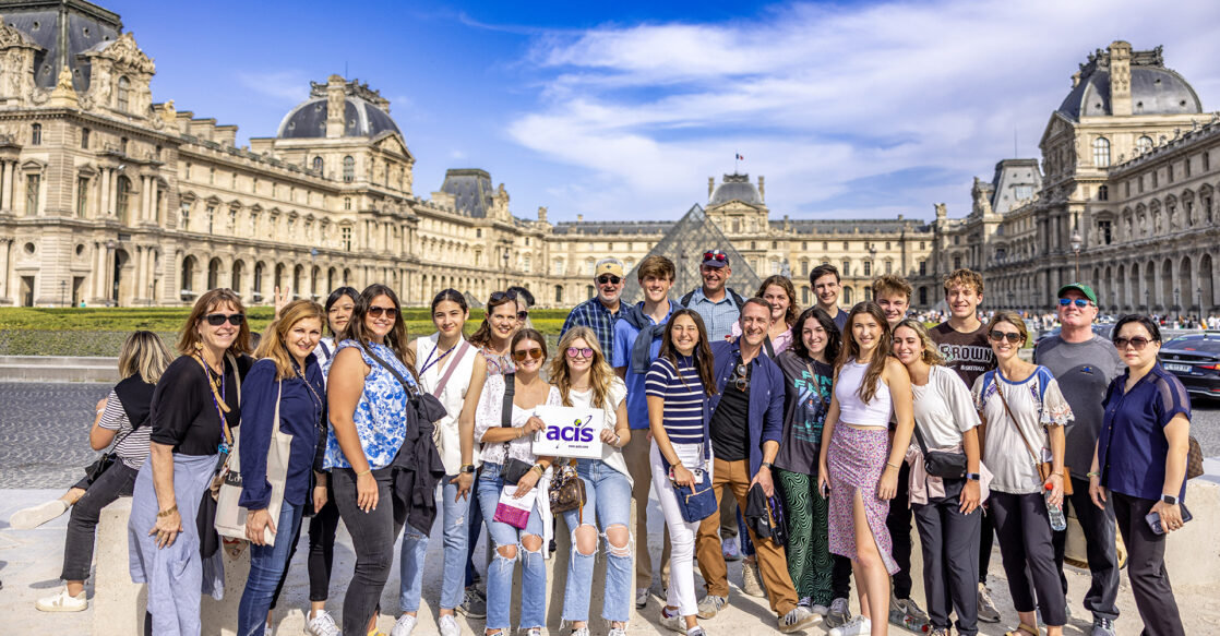 An ACIS group posing in front of the Louvre in Paris on a sunny day