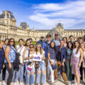 An ACIS group posing in front of the Louvre in Paris on a sunny day