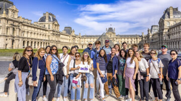 An ACIS group posing in front of the Louvre in Paris on a sunny day