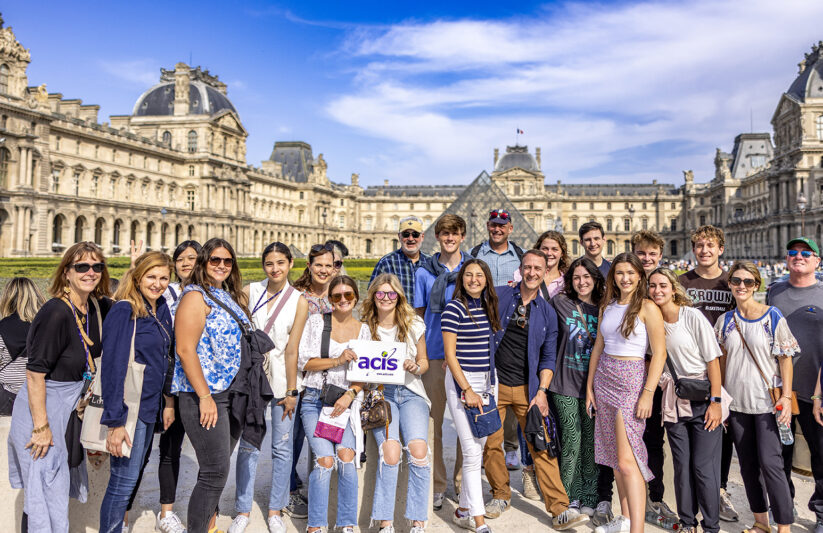 An ACIS group posing in front of the Louvre in Paris on a sunny day