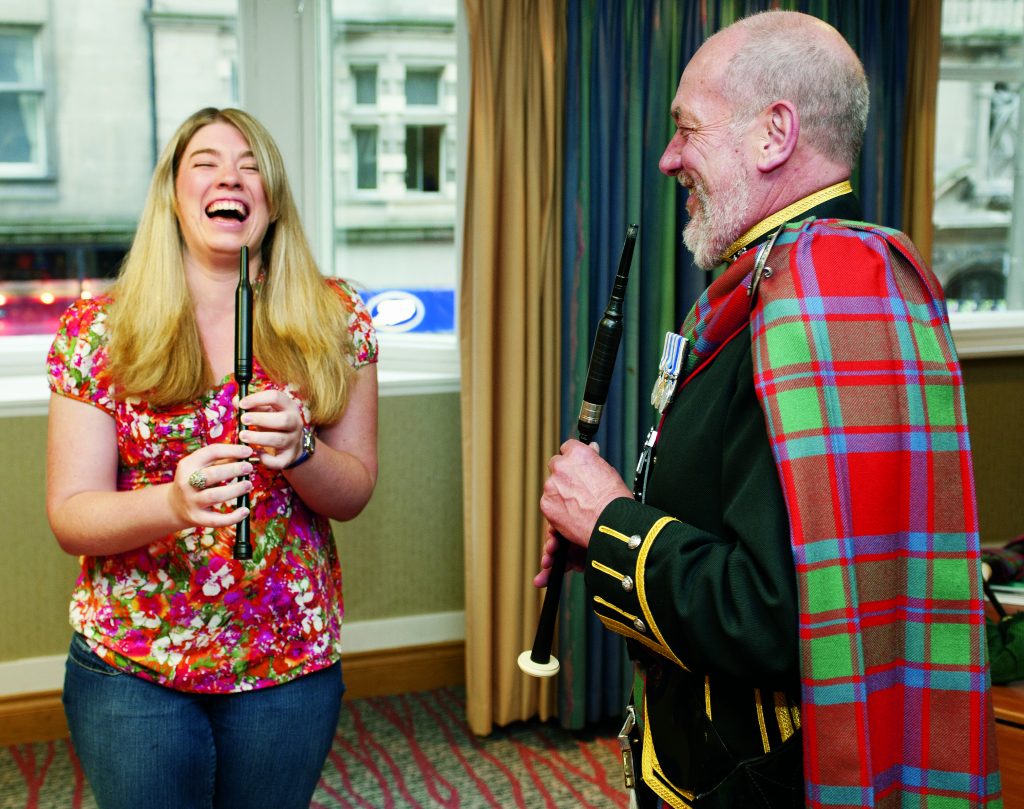 Girl learning to play bagpipes from a Scottish expert