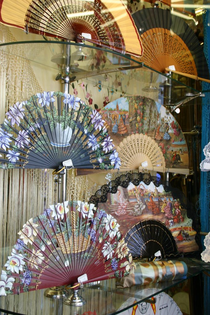 Painted hand fans on display behind glass